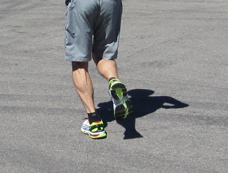 asics gel-kayano 21 - clearly seen on the outsole of the runner's right foot, the yellow...