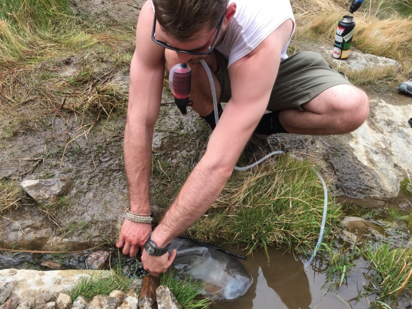 msr trail base - filling the trail base's bag in a shallow water source in death...